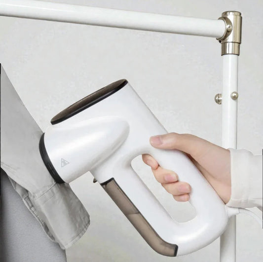 Main tenant un défroisseur électrique SkyGrip blanc pour repasser une chemise grise.