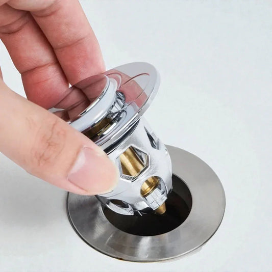 Main tenant une bonde de vidage chromée SkyGrip au-dessus d'un évier en inox.