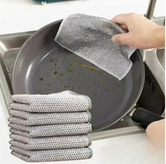 Main essuie SkyGrip nettoyant une poêle, pack de chiffons gris posés sur évier de cuisine.