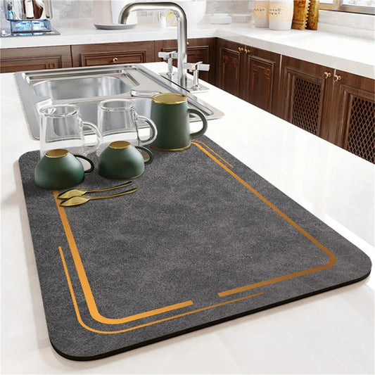 Tapis égouttoir SkyGrip gris avec liserés dorés sur plan de travail cuisine, tasses et couverts posés dessus